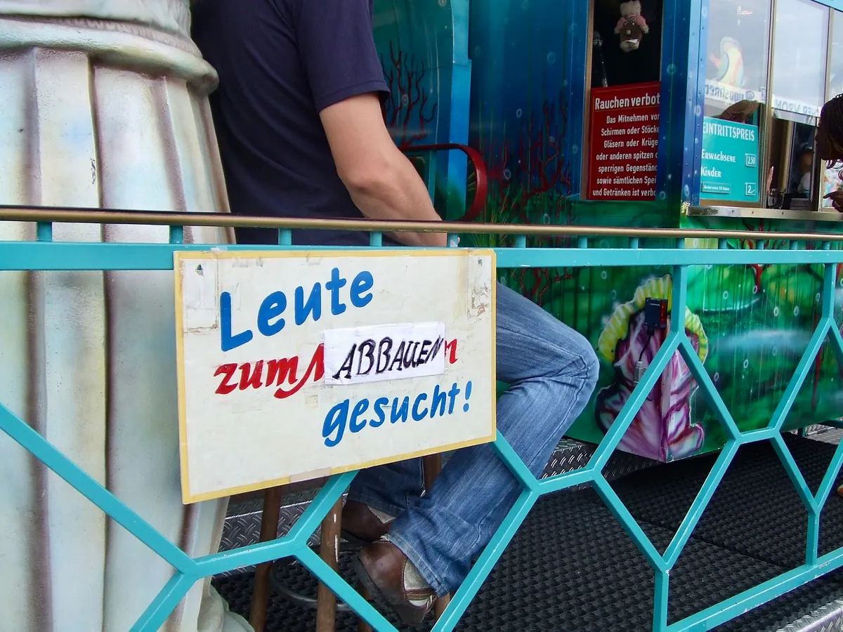 Ein Schild an einem Fahrgeschäft auf dem Oktoberfest sucht Personen für den Abbau.